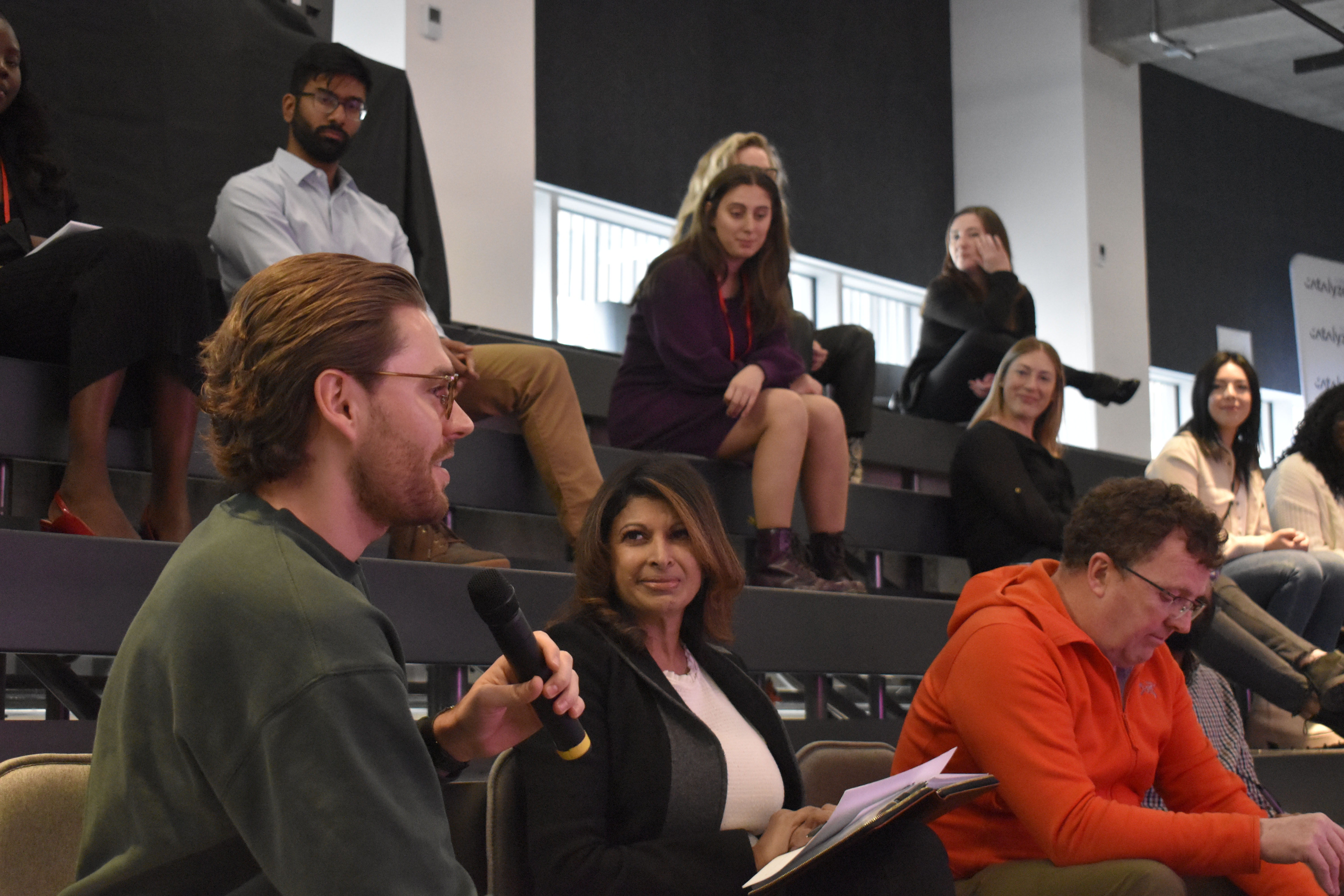 A student presents to the larger group from the bottom of bleachers